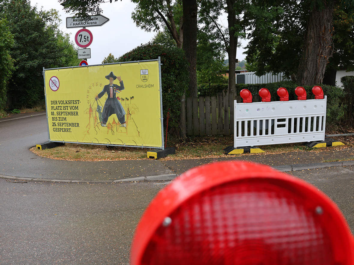 im Vordergrund ein Warnlicht, dahinter eine Straße und ein großes gelbels Banner